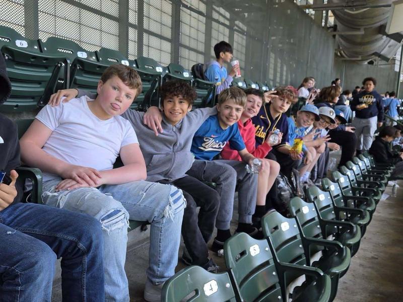 Group of boys sitting in stadium seats, some posing and smiling for the camera.