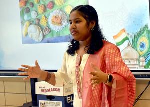 Student showcasing traditional Indian food in cultural attire.