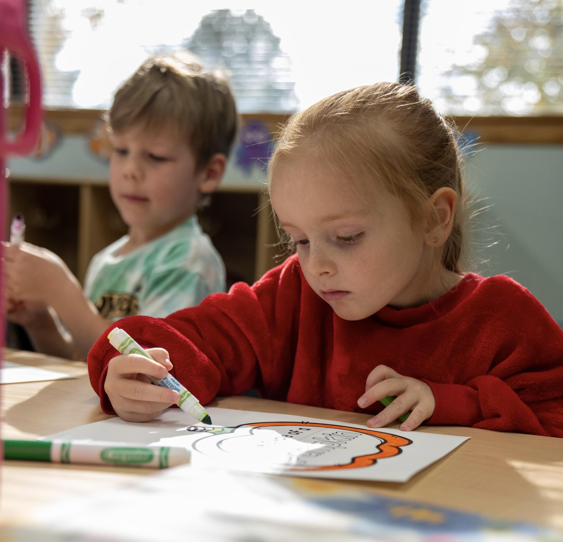 Two students coloring at a table