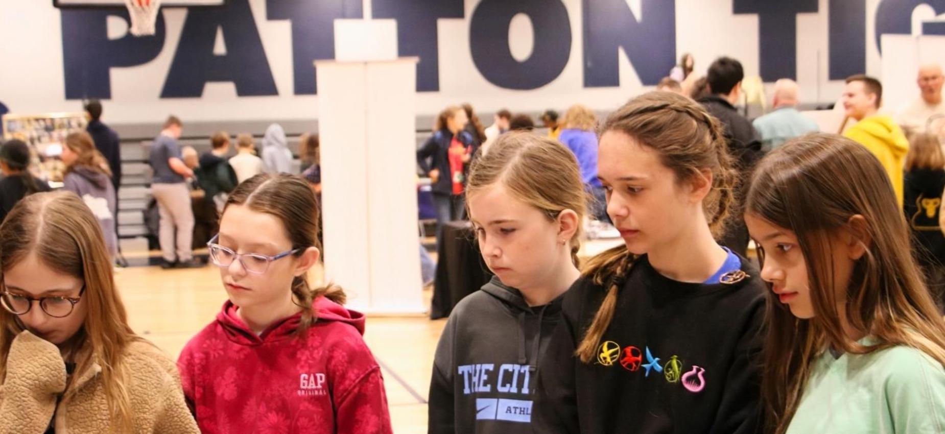 Five girls are engaged in conversation at a school event.