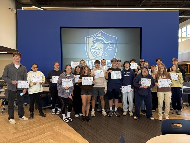 students holding certificates in front of knight head