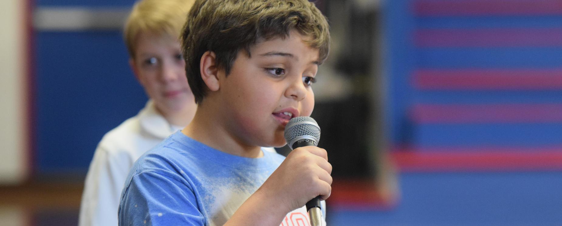 Elementary boy student singing with microphone