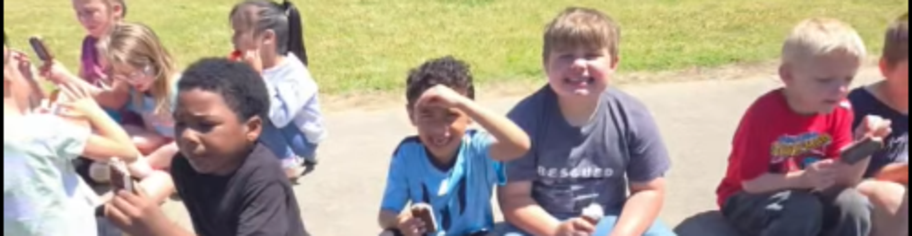 Picture of children enjoying ice cream while sitting outside.