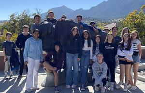 Students pose near a statue of a buffalo.