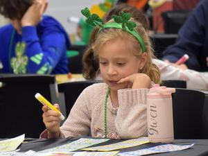 Girl with green accessories concentrating on her bingo cards.