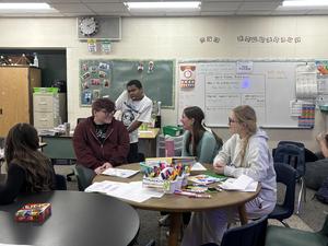 Students engaging in activities around a table in a lively classroom.
