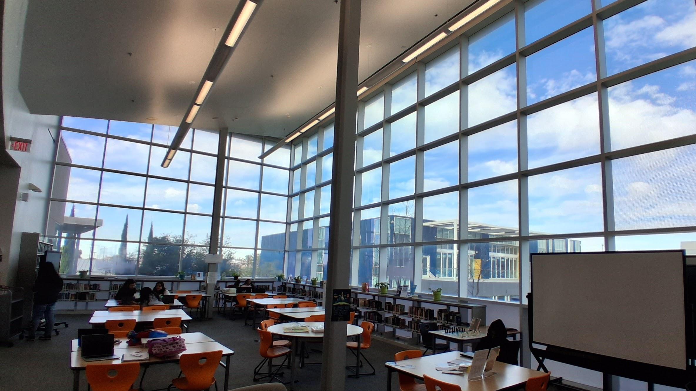 MCHS library, showing tall window walls, shelves and seating areas.