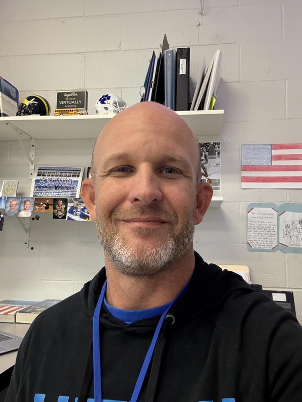 male teacher in a classroom smiling