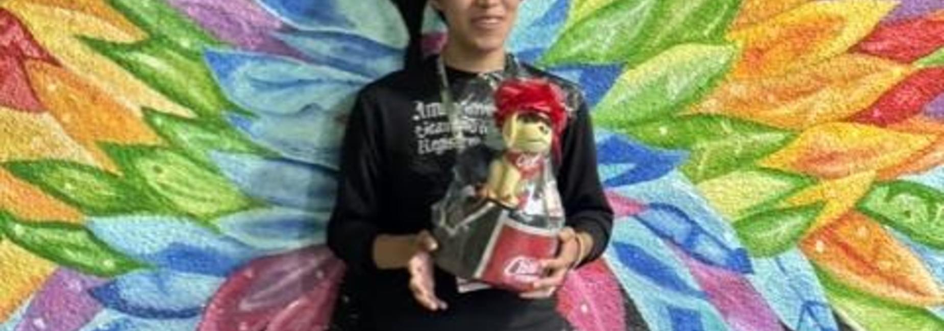 student with prize behind colorful wing painting
