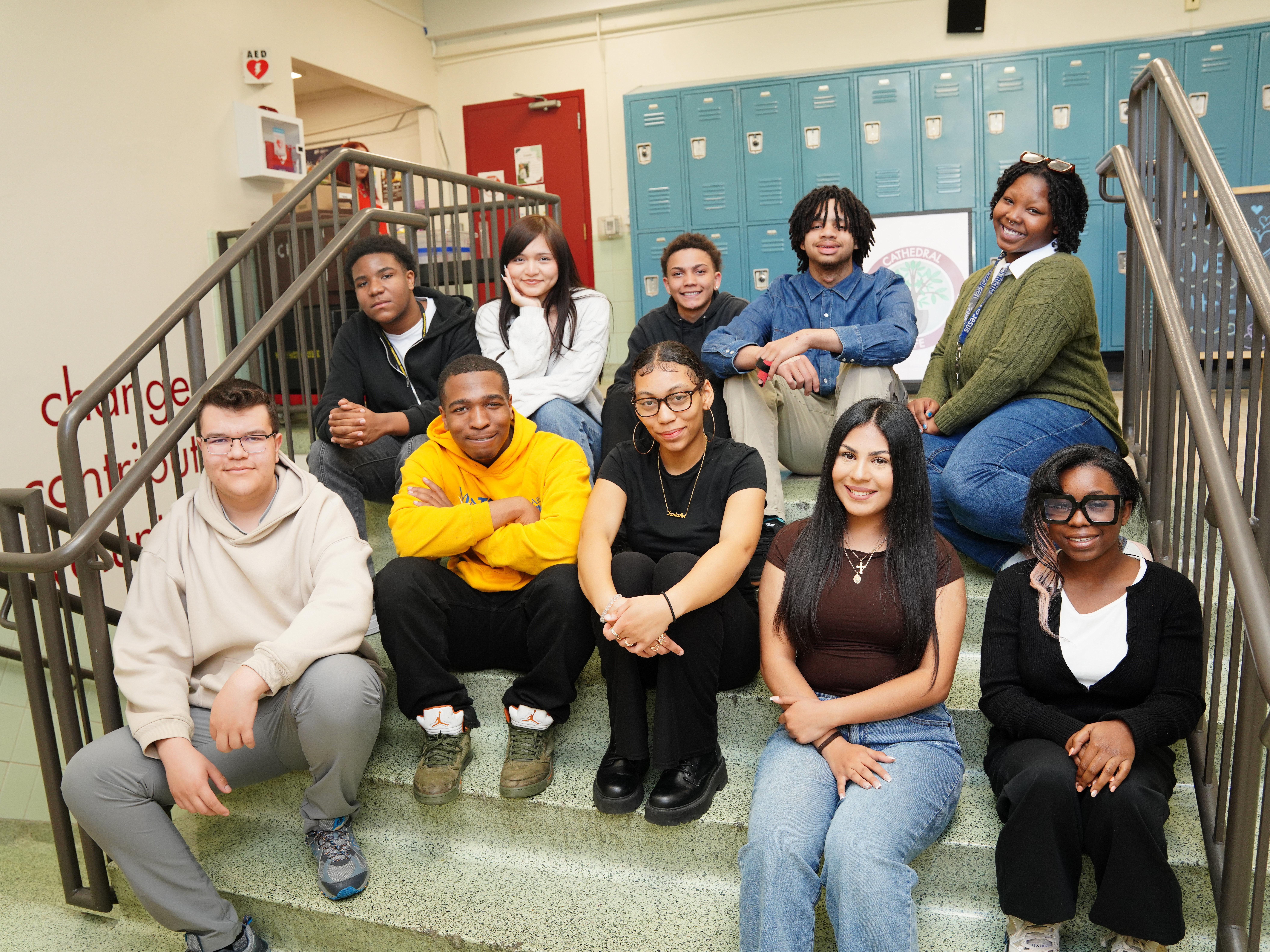 A group of students sitting on the stairs in the hallway of the school