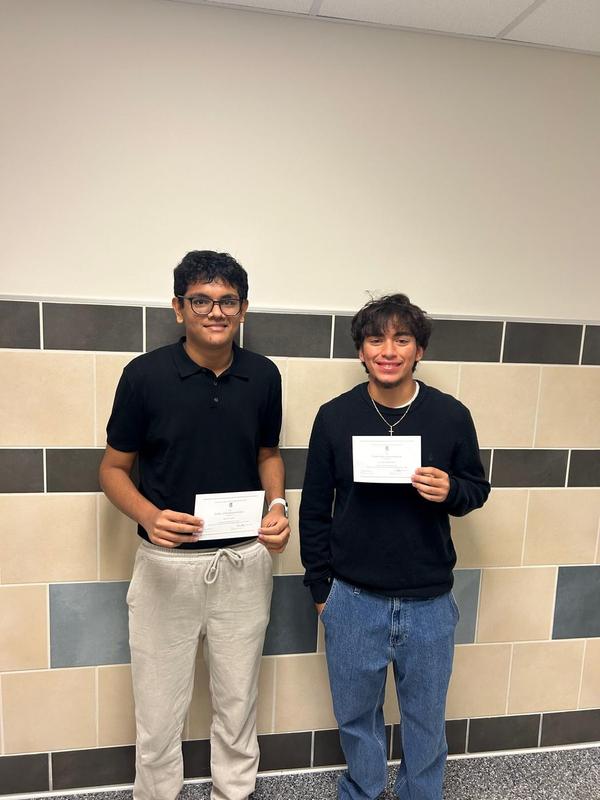 Image of 2 high school students holding their National Merit Commended Students certificate
