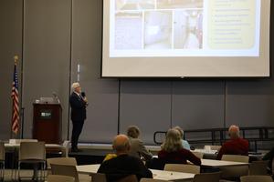 Looking at a lrage Power Point slide, Richard Martin talks about the infrastructure issues at the current school