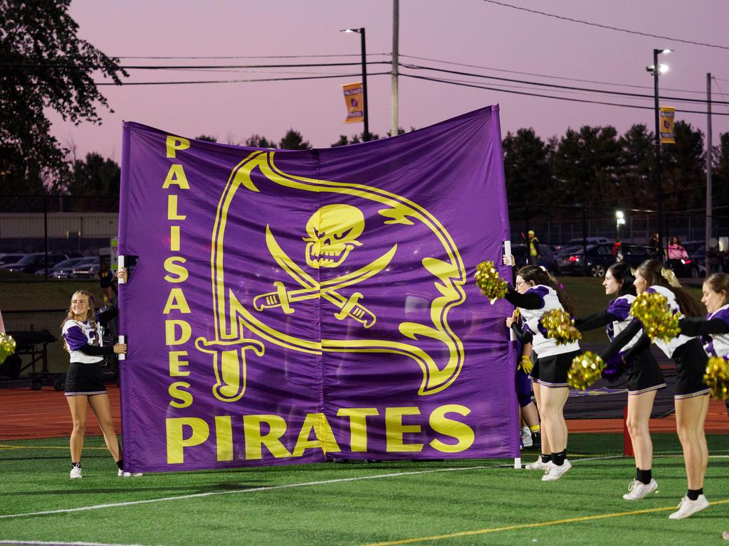 Cheerleaders holding up a Palisades Pirates banner for the football players to run through.