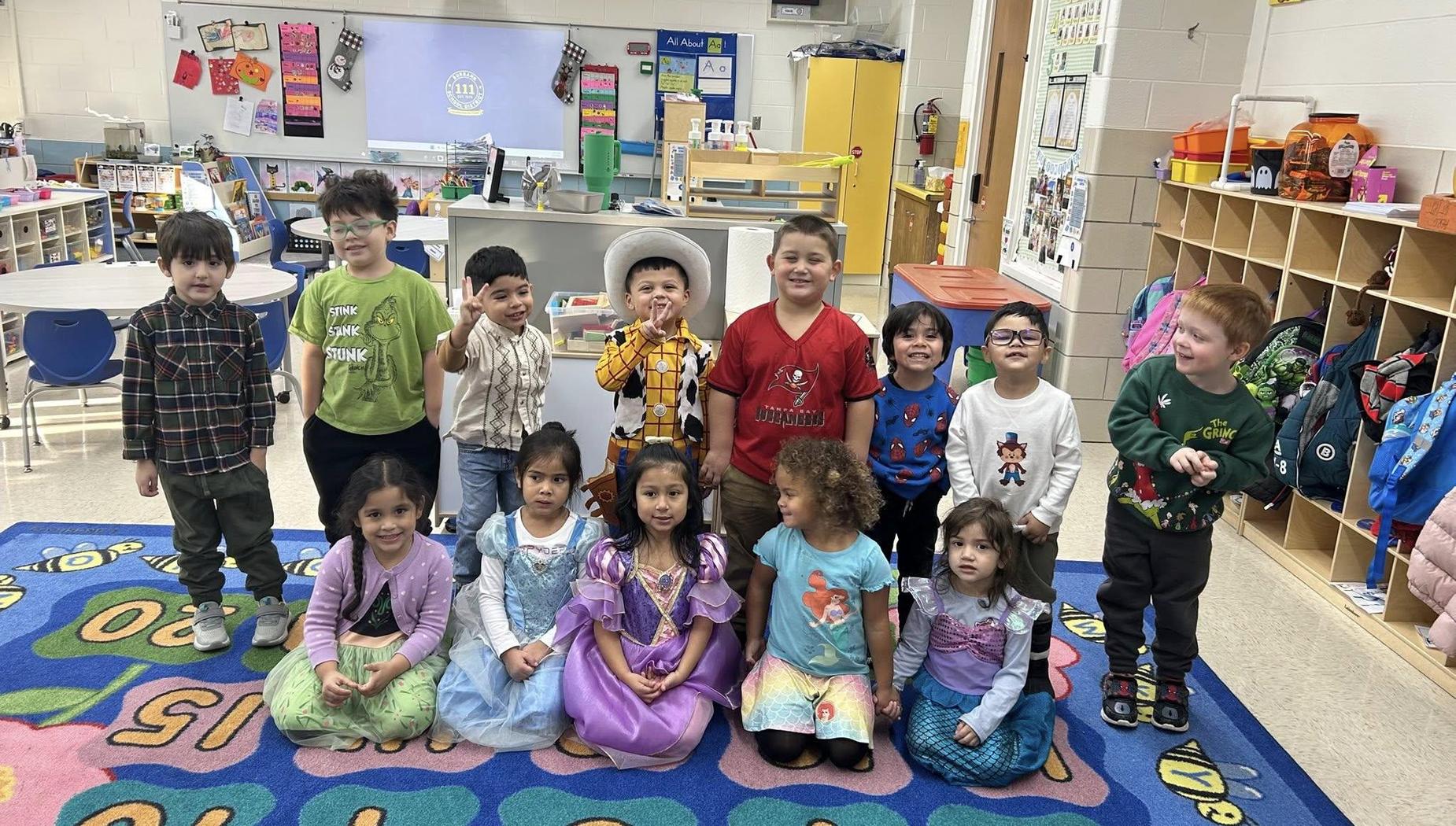 A group of children dressed in costumes posing together in a classroom.