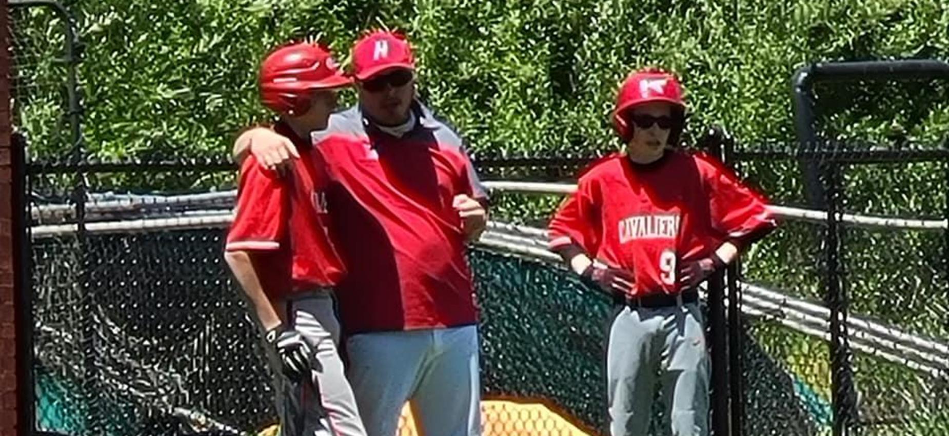 A coach talks to two baseball players during a game.