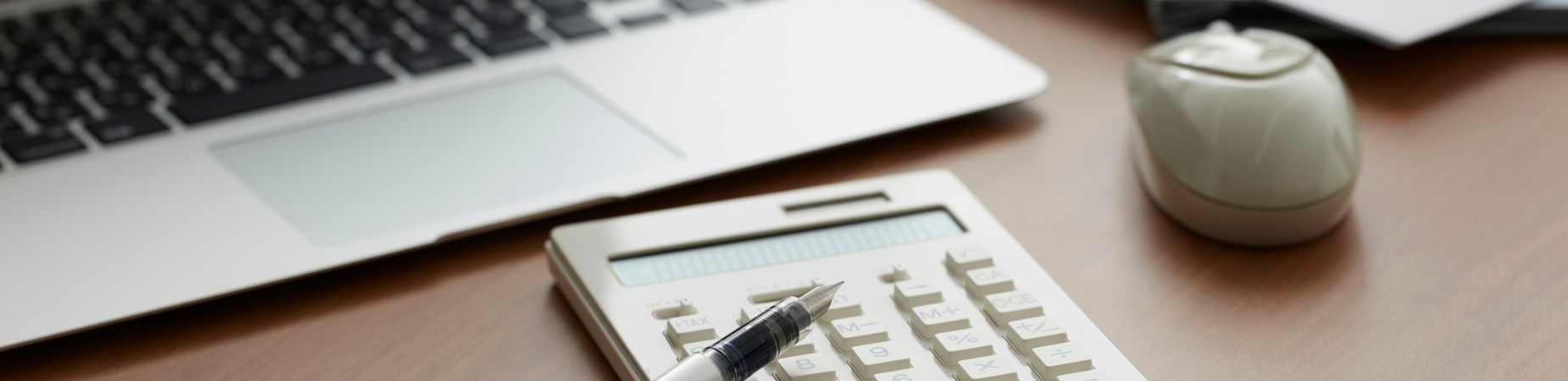 desktop with laptop, calculator, pen, mouse