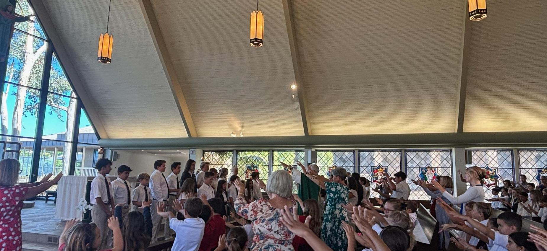 students and teachers raised hands over student council for blessing in church