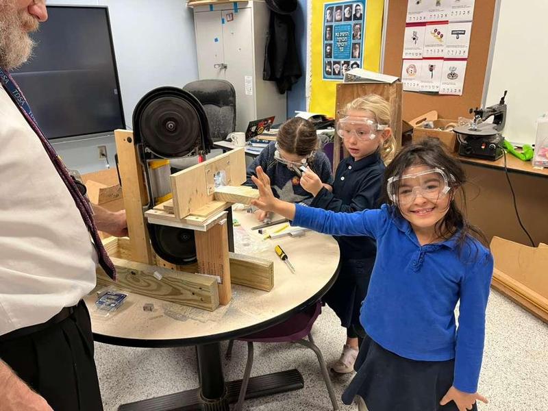 2nd grade girl using a saw to cut her metal rod to the right size.