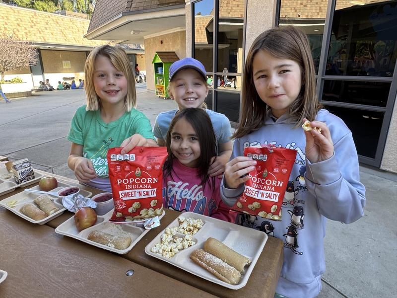 From left to right: Monterey Hills Elementary School second graders Iona Bruce, Lea Kolar, Zienna Cuadra (center wearing pink), and Reise Tuason enjoy a popcorn treat during lunch. (Photo Courtesy of South Pasadena Unified School District)
