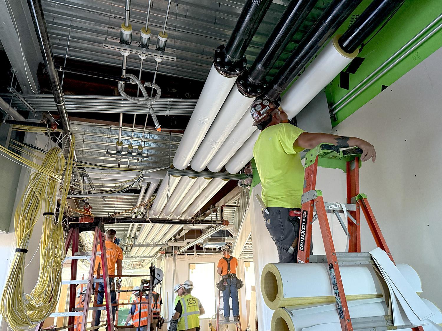 installing insulation on overhead water pipes