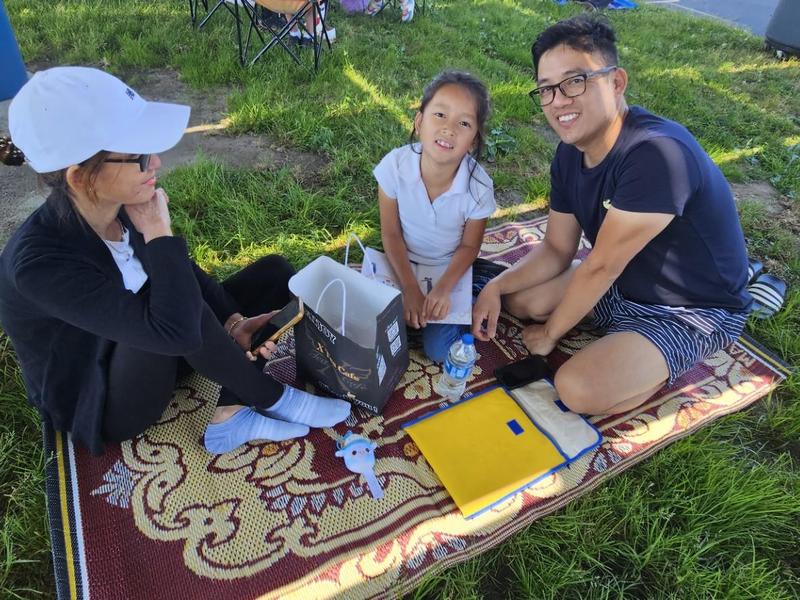 A family sitting on a blanket outdoors, smiling and enjoying time together.
