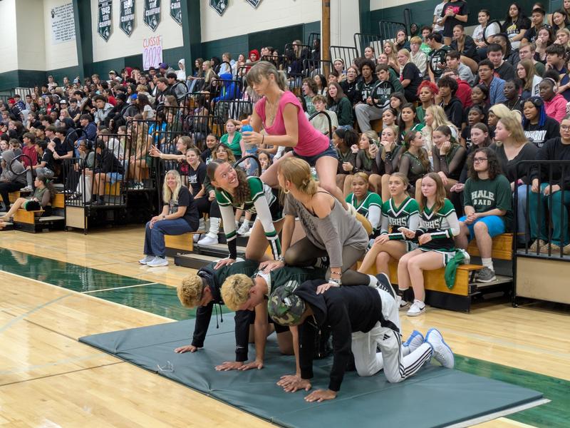 Students performing a stunt in front of an enthusiastic audience at a school event.