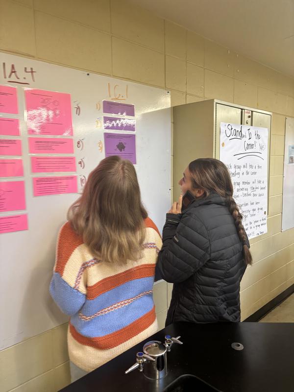 Two students looking at trivia cards on the wall