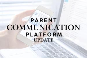 hand holding phone with laptop in the background