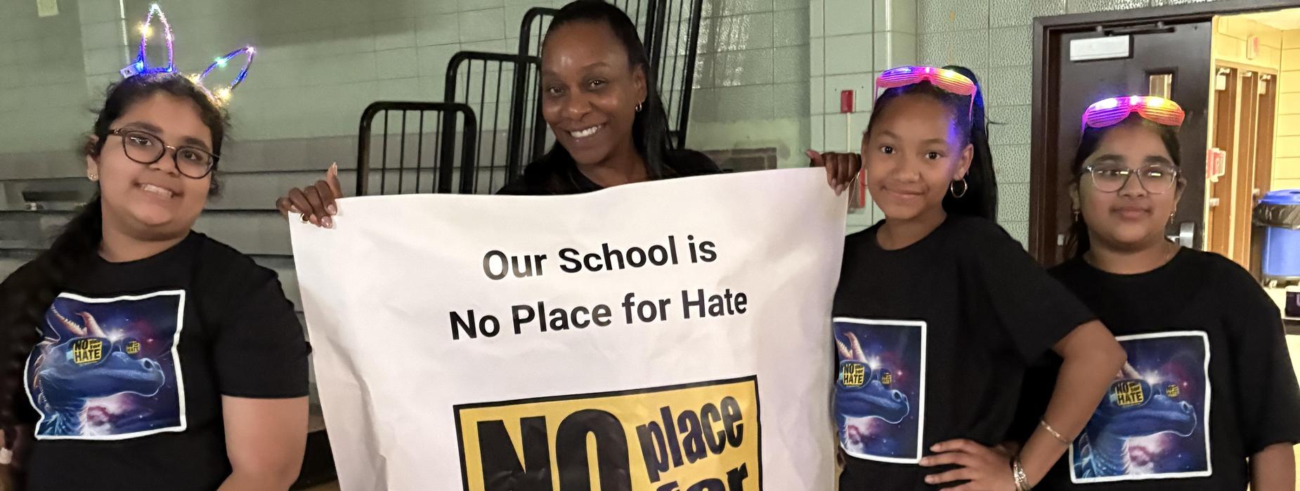 Four students holding a banner that promotes a message against hate.