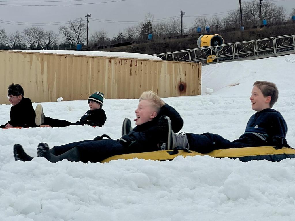 Middle school students inner tubing in the snow.