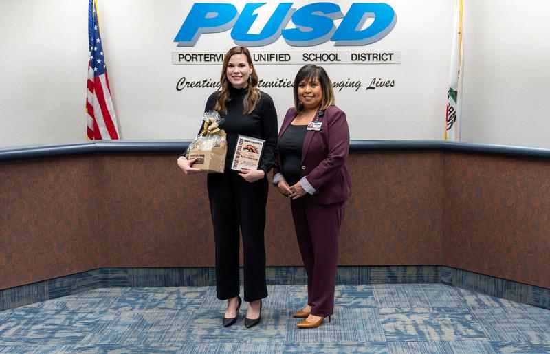 Kyla Chapman holds her Employee of the Year award and gift basket alongside a district administrator at the PUSD Board meeting.