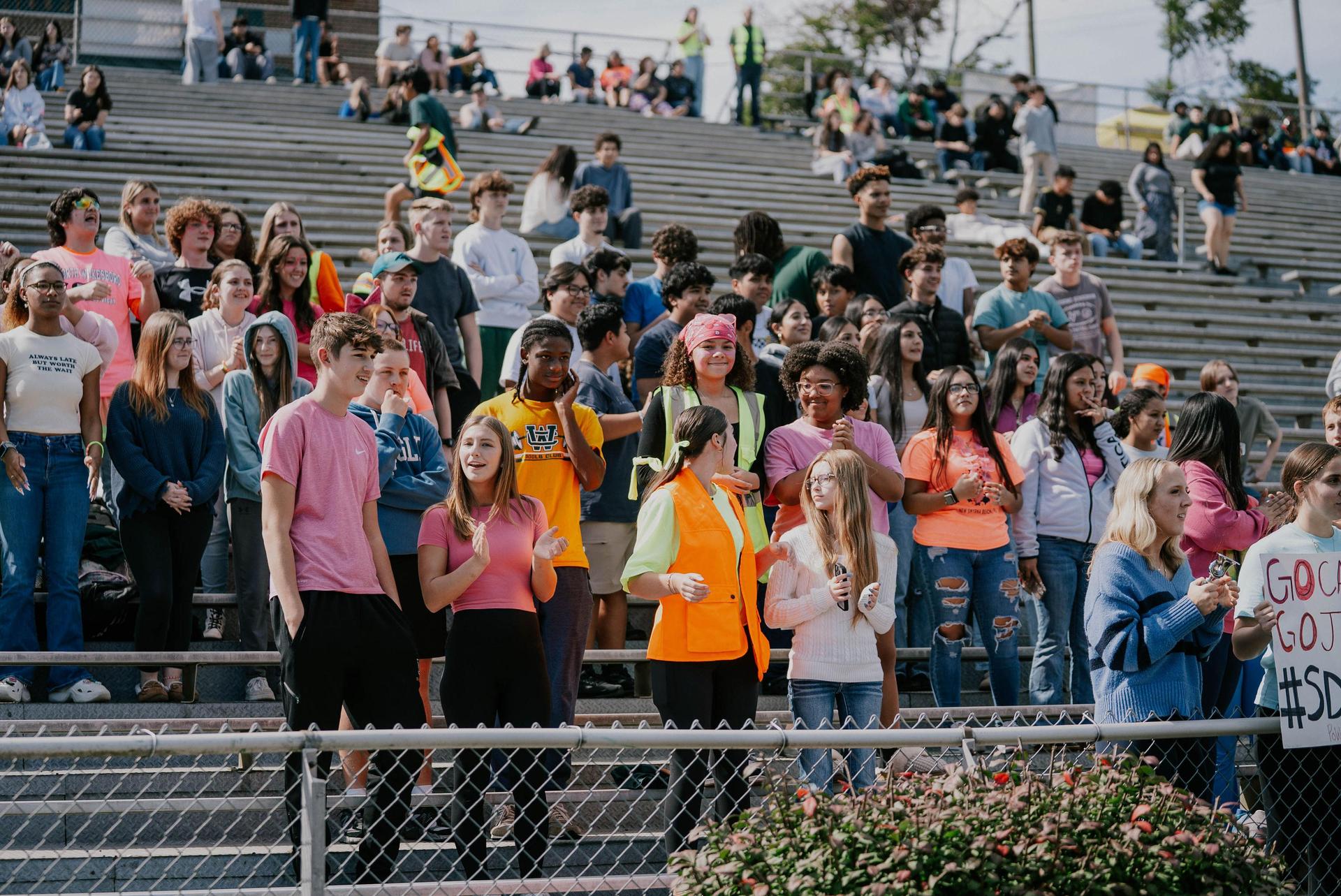 A large crowd of students cheering and celebrating in the stands during a school event.