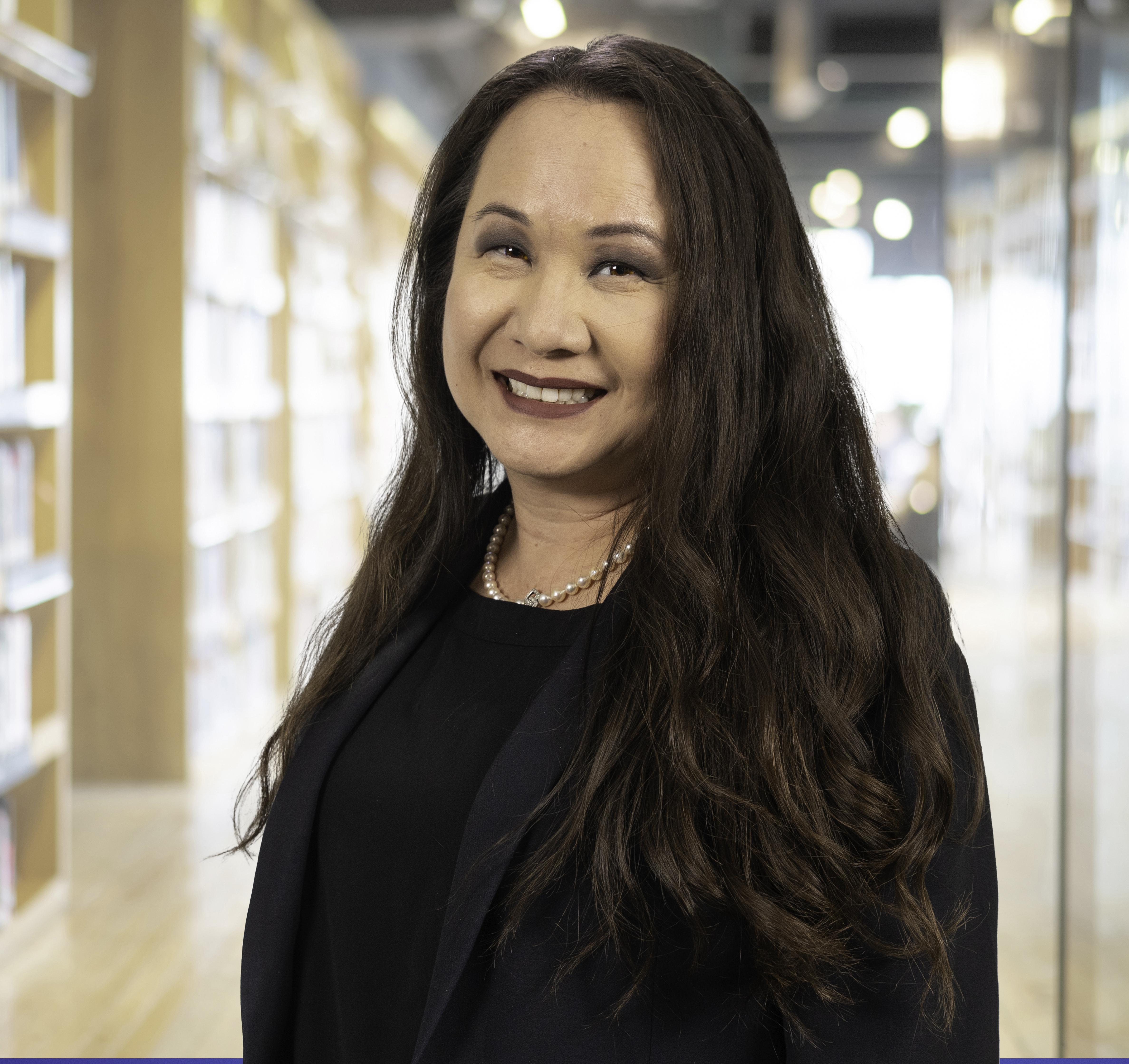 photo of the new CAO. Long hair wearing a navy suit, pearls and a broad welcoming smile
