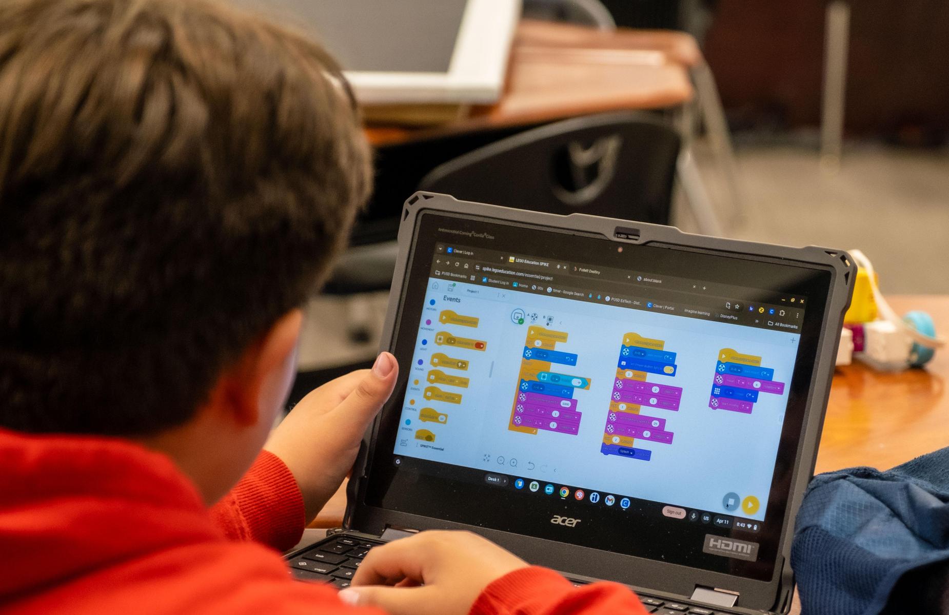 Photo taken from the rear showing a computer with programming app