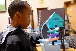 A child observes a colorful model displaying Bible verse Colossians 1:16.