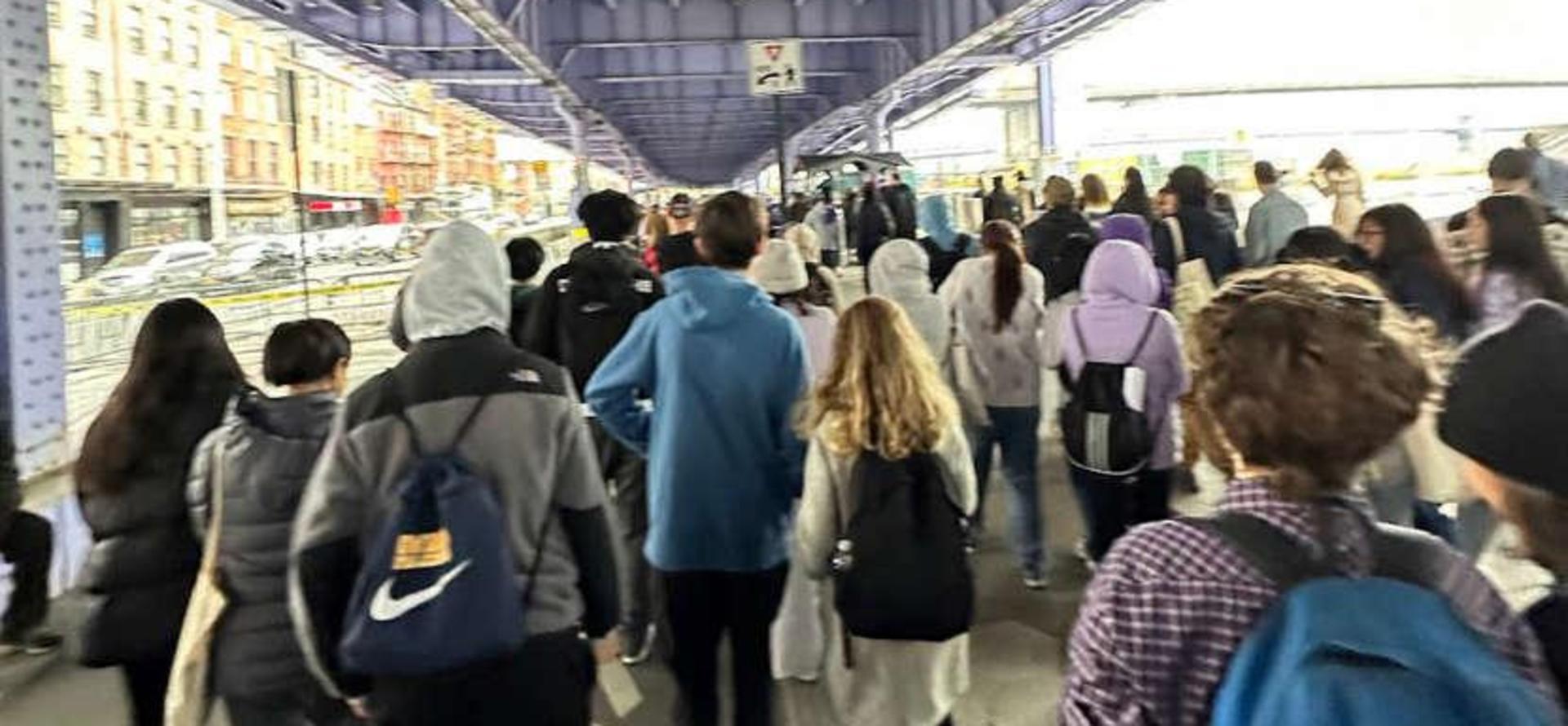 Crowd of people walking under a purple structure in a city.