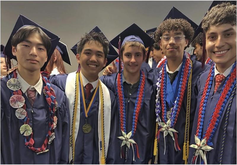 A group of graduates pose in their cap and gown