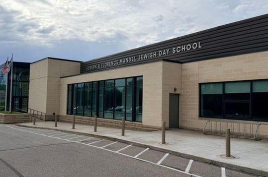 Exterior of a modern school building with large windows and an American flag.