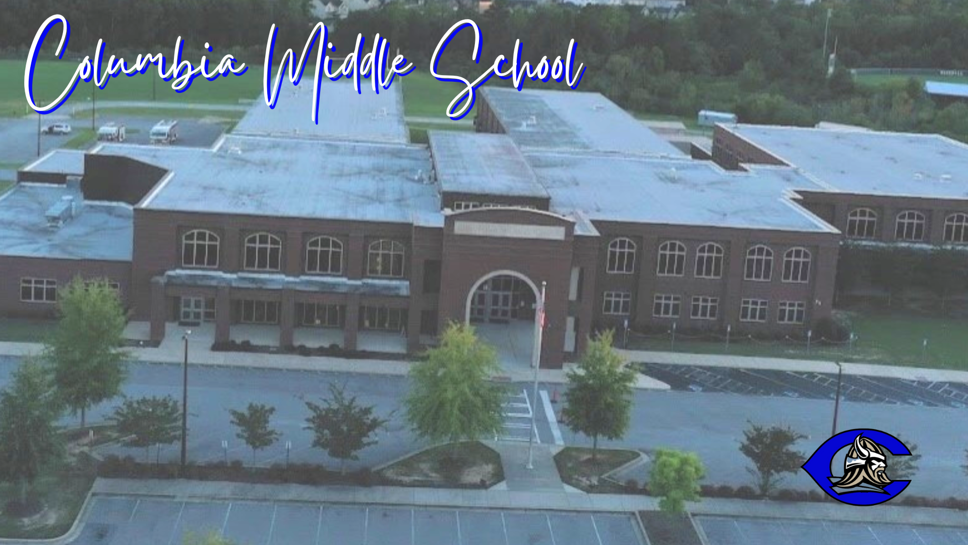 Aerial view of Columbia Middle School with trees and parking lot in front.