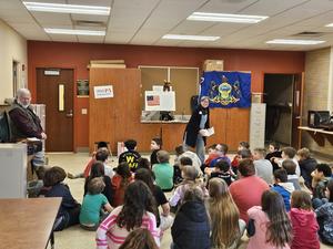 Juniata 4th graders seated listening to a special assembly by retired teachers.