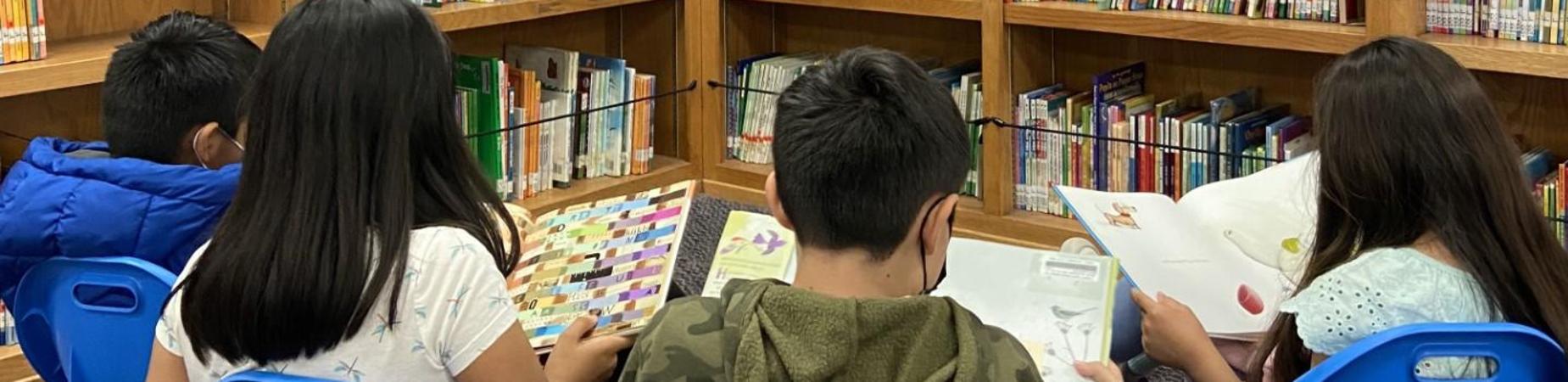 Four students reading with their backs turned to the camera