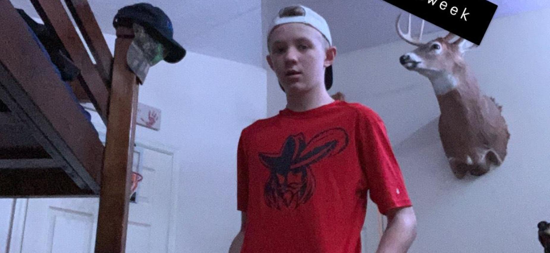 A student stands in a bedroom.