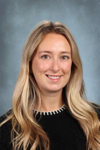 Smiling woman with long blonde hair, wearing a black sweater.