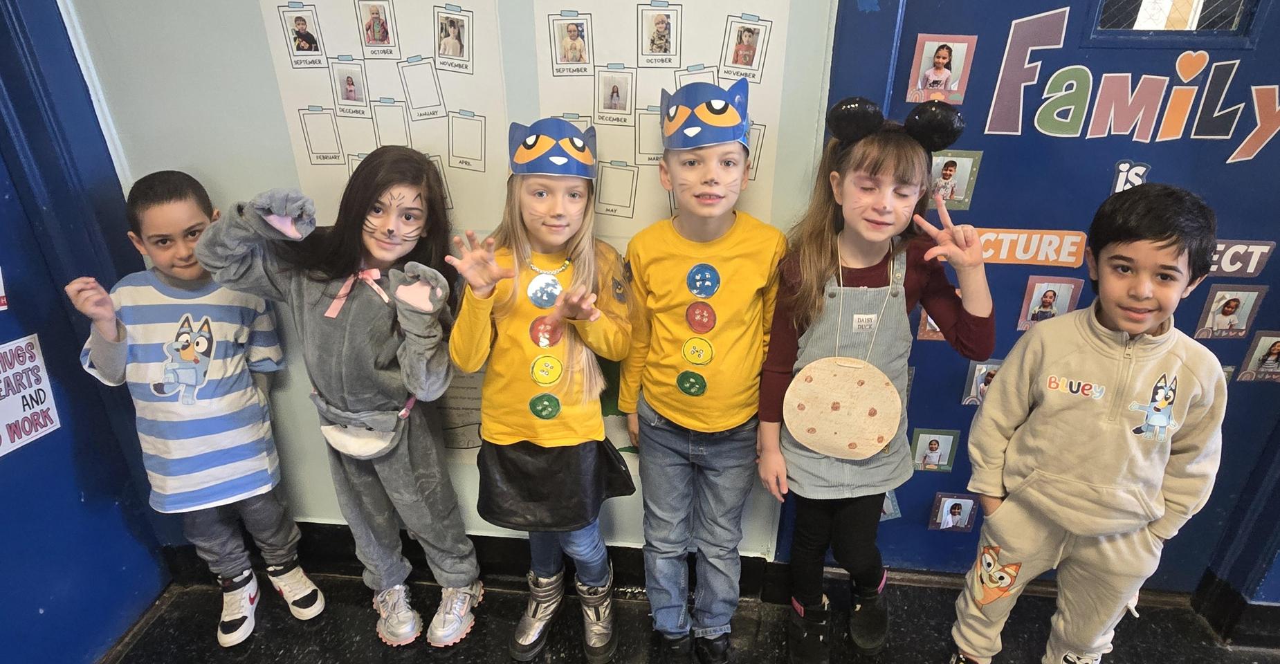 Group of children in costumes posing together in a school hallway.