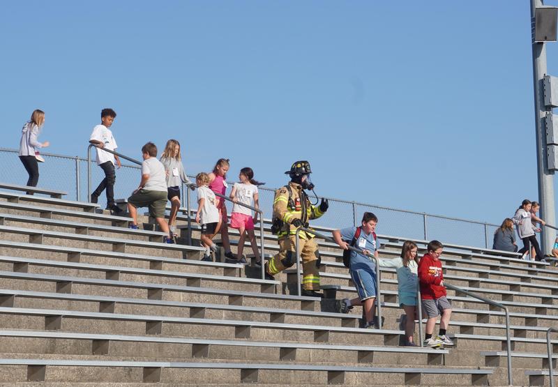 Page students climb up and down the steps in Bob White Stadium along with a firefighter fully attired in turnout gear.