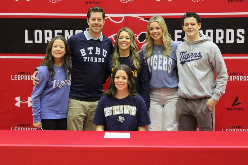 A group of six people smiling together at a signing event for ETBU Tigers.
