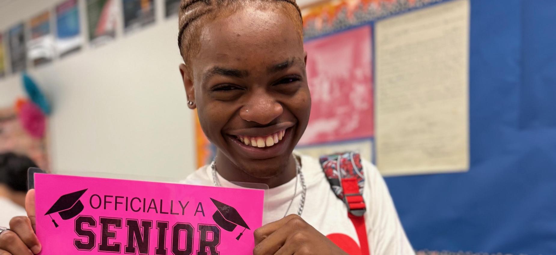 A students holding an "Officially a senior. My last day of school" sign
