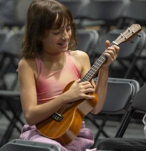 Girl in pink shirt playing ukulele