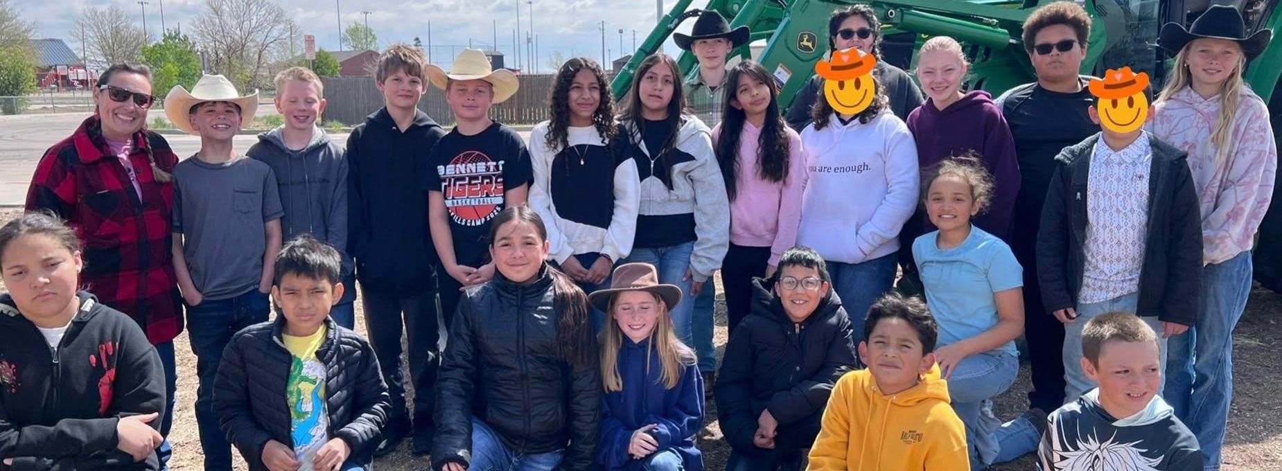 Group of students outdoors wearing cowboy hats, posing together.