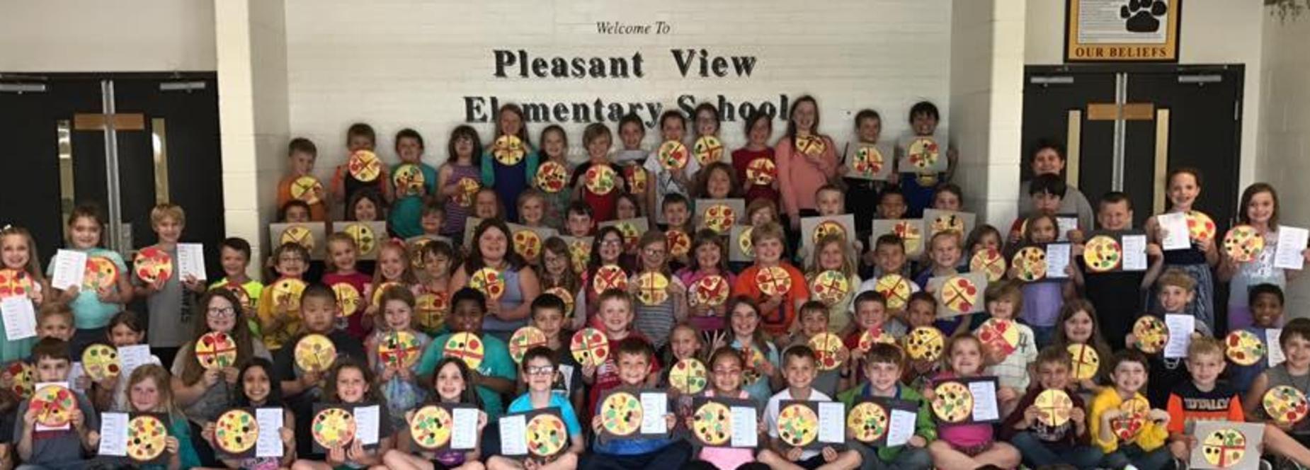 Children smiling holding pizza fractions.